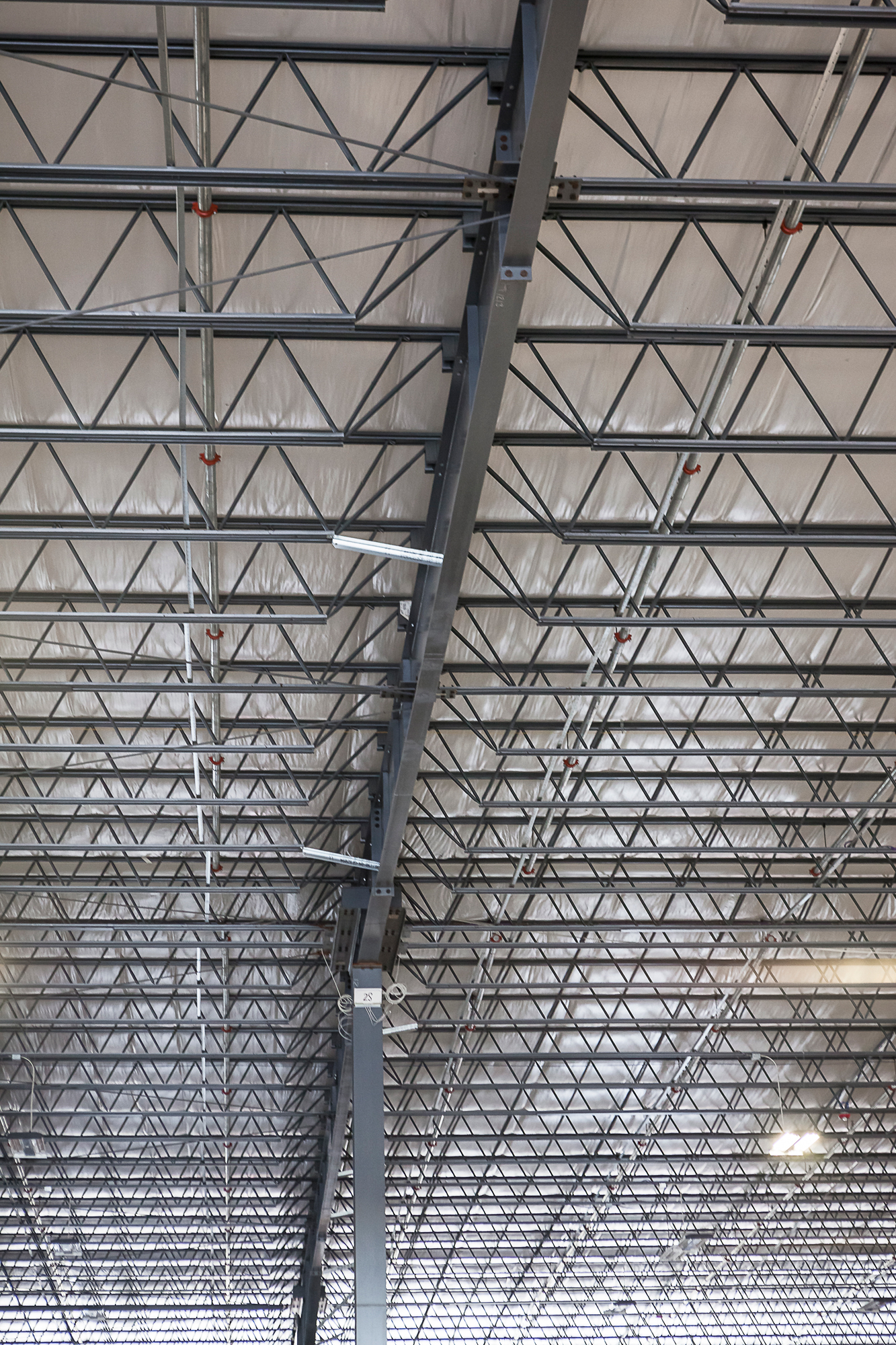 Interior view of steel roof trusses and columns spanning a large metal building